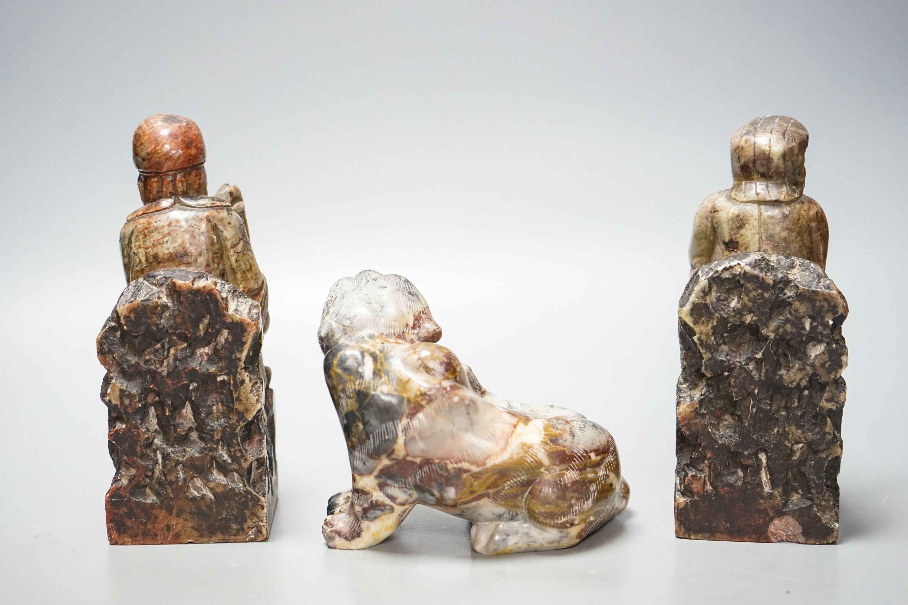 A pair of Chinese soapstone figures of immortals, modelled seated on rocky bases and a similar figure of tiger, 12cm